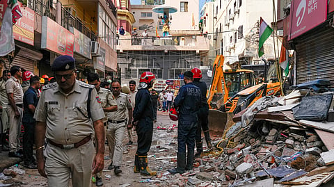 Rescue personnel stand near debris during a rescue operation on the second day after a 50-year-old five-storey building housing a boys' hostel collapsed in a congested bylane in Satya Niketan near Delhi Universitys south campus, Monday, Sept. 7, 2026.