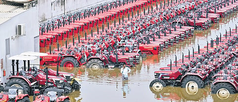 A man wades through floodwaters in a submerged tractor dealership stockyard following a rise in the water level of the Punpun river in Patna 