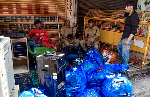 Students and police personnel sit near belongings as students vacate their PGs adjacent to the Satya Niketan PG building which collapsed near Delhi University's South Campus, following a demolition order by the Municipal Corporation of Delhi (MCD), in New Delhi, Tuesday, Sept. 8, 2026.