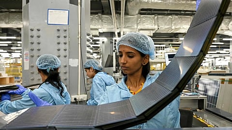 Employees inspect photovoltaic cells used in solar panels at an Adani Group factory in Mundra, India