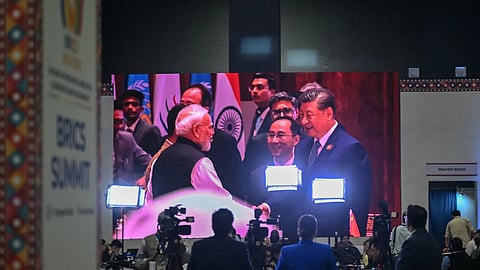 Mediapersons watch a digital screen showing China's President Xi Jinping meeting with India’s Prime Minister Narendra Modi during the 18th BRICS Summit at the Bharat Mandapam in New Delhi on Sunday