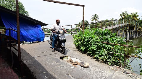A biker carefully steers clear of a crack on the Eroor–Chambakkara bridge.
