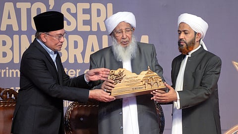 Kanthapuram A P Aboobacker Musaliyar presenting a memento to Malaysian Prime Minister Anwar Ibrahim at the function held at Markazu Saqafathi Sunniyya at Karanthur in Kozhikode on Sunday. Also seen is Abdul Hakkim Azhari.