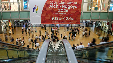 Commuters walk past a banner as the city prepares for the 20th Asian Games ahead of the Opening Ceremony on Saturday 