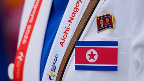 A North Korean offical wears their national flag during a ceremony for the Asian Games at the athletes village in Nagoya, Japan, Friday, Sept. 18, 2026.