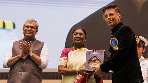 President Droupadi Murmu presents the award for 'Best Popular Film Providing Wholesome Entertainment' to filmmaker Karan Johar as Union Minister for Information and Broadcasting Ashwini Vaishnaw looks on during the 71st National Film Awards, in New Delhi.
