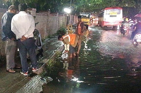 Civic workers drain out stagnant water on a road at Sampangiram Nagar in Bengaluru on Monday 