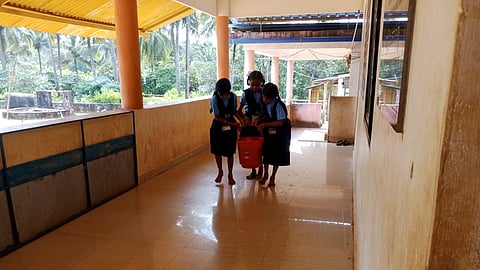 Students carry water in a bucket to use in the toilet.