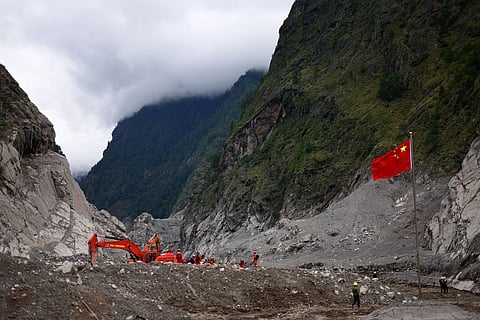 Rescue workers conduct search and rescue operations, near a Chinese national flag, at the core disaster-hit area at Gyirong Port amid rescue efforts following the August 26 mudslide, during an organised media tour in Shigatse, Tibet Autonomous Region, China, Sunday, Sept. 6, 2026.