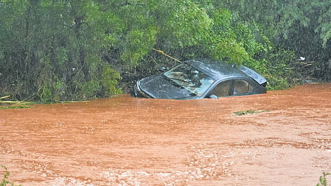 A car parked on the road at Nunna mango market was washed away as Pedavagu was in spate after heavy rain; a waterlogged road in Vijayawada.