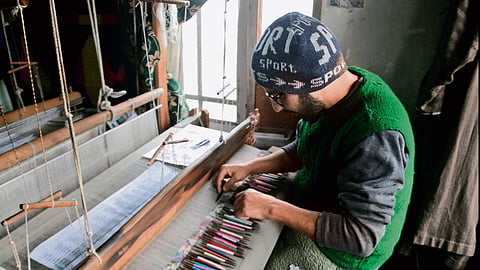 An artisan weaving a Kani shawl