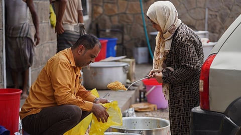 Volunteer Naseem Al-Adini, right, provides free meals to displaced people at the Al-Akdaf camp in Taiz, Yemen, Saturday, Sept. 26, 2026.
