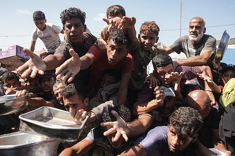 Displaced Palestinians gather to receive hot meals distributed by a charity kitchen in Khan Yunis in the southern Gaza Strip on September 25, 2026.