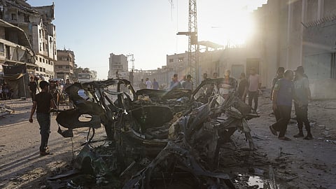Palestinians inspect the wreckage of a car after it was hit by an Israeli strike in Gaza City, Sunday, Sept. 27, 2026.