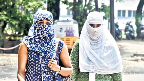 Two women cover their faces for protection from heat as they walk on a street in Chennai on Monday 