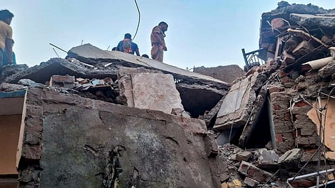 A police official and people stand on a damaged structure after a domestic LPG cylinder exploded, causing a two-storey building to collapse, at Malwan, in Fatehpur district, Uttar Pradesh, Monday, Sept. 28, 2026.