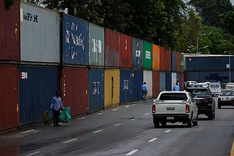 Vehicles drive past shipping containers placed by authorities to seal off an area ahead of a plan protest march by the supporters of imprisoned former Prime Minister Imran Khan demanding his release, in Islamabad, Pakistan, Monday, Sept. 28, 2026.