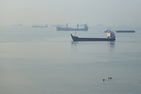 People wade in the water as cargo ships are anchored in the Strait of Hormuz off Bandar Abbas, Iran, early Monday, Sept. 28, 2026.