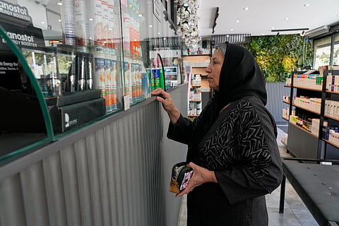 A woman receives her medicine at a pharmacy in Tehran, Iran, Friday, Aug. 21, 2026.