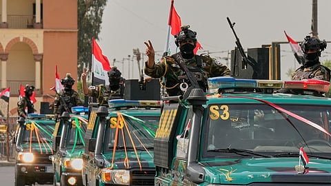 Iraqi security officers flash victory signs as they ride on vehicles decorated with national flags and ribbons during a convoy celebrating the complete withdrawal of US troops from Iraq, in Baghdad, Iraq, Wednesday, Sept. 30, 2026.