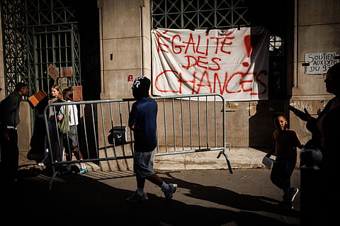 A student carries a barrier in front of a banner which reads "equal opportunities" suspended on the front of Louis-le-Grand high school in central Paris, on October 2, 2026.