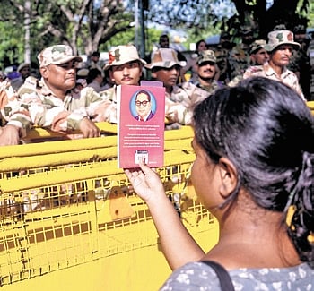A demonstrator shows a book written by Dr B R Ambedkar to security personnel during the protest on Saturday 