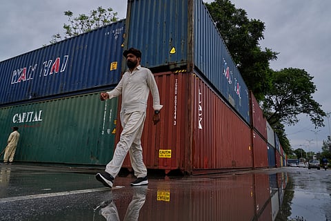 A resident walks past shipping containers placed by authorities to seal off an area ahead of a plan protest march by the supporters of imprisoned former Prime Minister Imran Khan demanding his release, in Islamabad, Pakistan, Monday, Sept. 28, 2026.