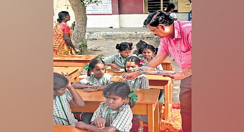 S Vijayakrishnan distributes sweets to girl students seated on benches provided through his charitable
trust in a village school. 