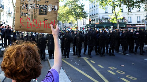 Protester holds a “500 arrests, so revolution” placard during a high-school student protest in Paris on October 6, 2026.