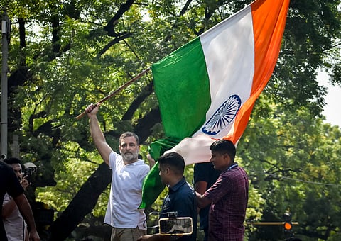 Rahul Gandhi waves Indian national flag atop a police barricade in New Delhi.