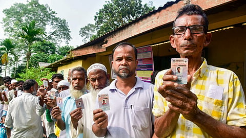 Voters display their voter identity cards as they stand in a queue to cast their votes at a polling booth during the Nagaon Lok Sabha constituency by-election, in Morigaon district, Assam, Tuesday, Oct. 6, 2026.
