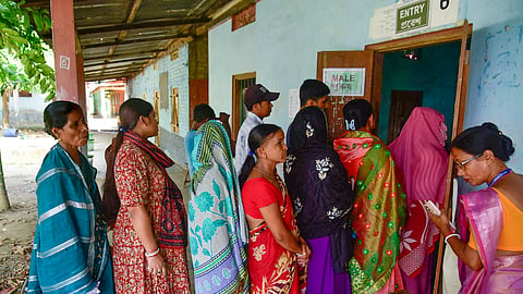 Voters stand in a queue to cast their votes for the Nagaon Lok Sabha by-poll, at a polling station in Buraburi, Morigaon district, Assam, Tuesday, Oct. 6.