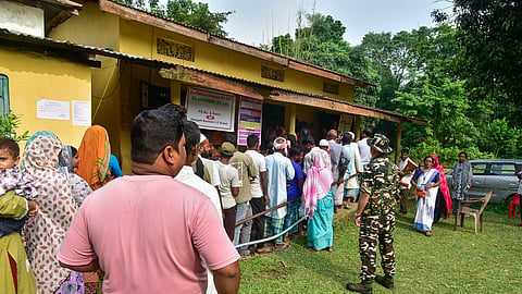 Security personnel stand guard as voters queue to cast their vote for the Nagaon Lok Sabha by-election at Hatigarh, in Morigaon, on Tuesday, Oct. 06, 2026.