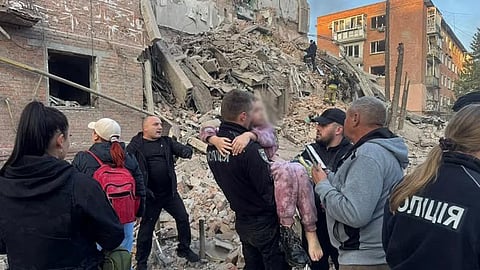 A handout picture taken and released by Ukraine's National Police on October 7, 2026 shows rescuers carrying a child away from a residential building destroyed following a Russian missile strike in Pryluky, Chernihiv region, amid the Russian invasion of Ukraine.