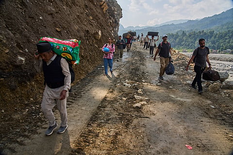 People carry their belongings as they walk toward their villages after flash floods damaged roads in Nuwakot, Nepal, Friday, Oct. 2, 2026. 