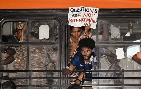 A demonstrator shouts slogans from inside a police bus after being detained during a protest organised by the Cockroach Janta Party (CJP), at Connaught Place, in New Delhi, Saturday, Oct. 10, 2026.