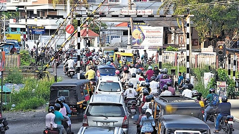 Vehicles jostle to cross over as the railway gate at Kureekad opens after a train passes on Sunday evening 