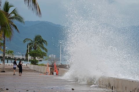Tourists take photos of a water splashing against the wall as Hurricane Simon approaches Puerto Vallarta, Mexico, Sunday, Oct. 11, 2026.