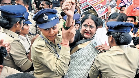 Police remove a BJP women’s wing leader during a protest outside the Congress office  in Bengaluru on Monday.
