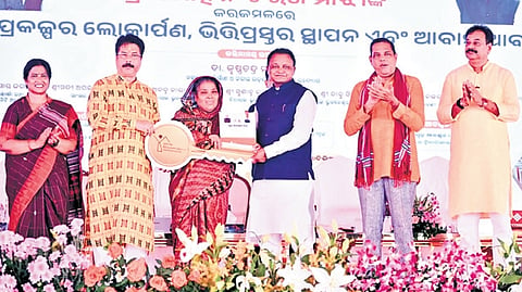 CM Mohan Charan Majhi handing a key to a woman beneficiary under PMAY-U