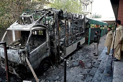 Security personnel inspect burnt vehicles at the National Database and Registration Authority (NADRA) office following clashes, in Bara on the outskirts of Peshawar on October 14, 2026.