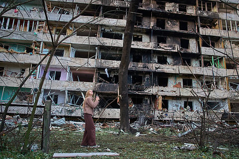 A young woman reacts as she looks at her damaged home after Russia's night missile attack in Kyiv, Ukraine, Wednesday, Oct. 14, 2026. 