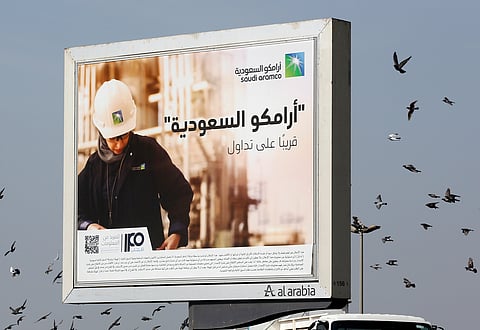 FILE -Birds fly over a billboard advertisement for Saudi Arabia's state-owned oil giant Aramco, with Arabic that reads, "Saudi Aramco, soon on stock exchange," in Jiddah, Saudi Arabia. 