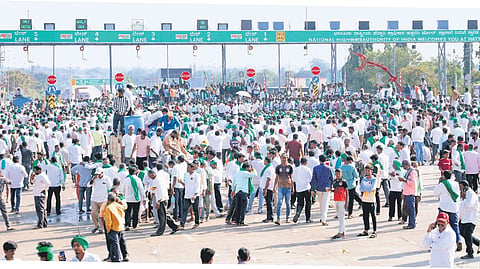 Thousands of sugarcane farmers gather at Hattargi toll plaza on the Karnataka-Maharashtra border on Wednesday. Later, they called off the blockade and undertook a padayatra to Union Minister Pralhad Joshi’s residence in Hubballi.