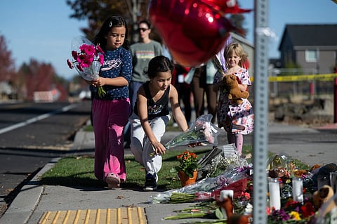 Children place flowers at a makeshift memorial outside Silver Rail Elementary in Bend, Ore., Friday, Oct. 16, 2026, a day after a deadly shooting.