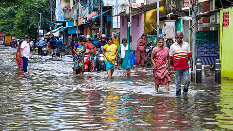 Commuters wade through a waterlogged street following heavy rain, in Chennai, Sunday, Oct. 18, 2026.