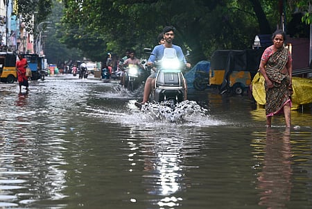 People wade through flooded street at Pattalam in Chennai after the city witnessed heavy rain on the early hours on Sunday.