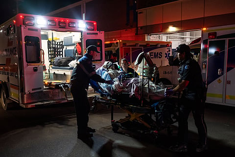 Paramedics load an injured person into an ambulance at the Wainwright Health center after a fire at Canadian Forces Base Wainwright, outside of Wainwright, Alberta Saturday, Oct. 17, 2026.