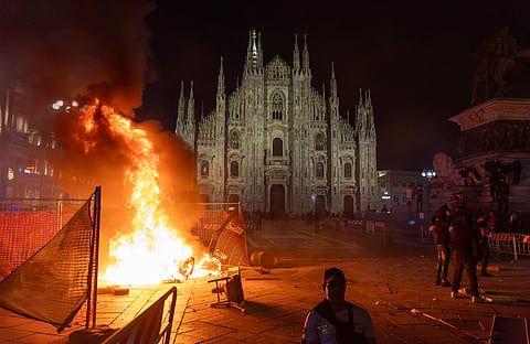 A fire burns following clashes between police and "Italia in Piazza" protesters in front of the Milan Cathedral in Milan, Italy, on Saturday, Oct. 17, 2026.