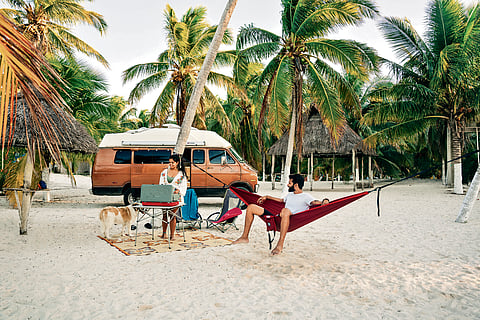 Smriti and Kartik with their campervan parked on a beach